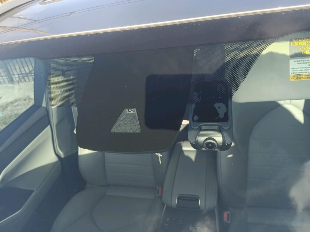 Windshield-mounted camera housing with a separate dash camera beside it.